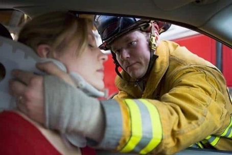 Firefighter rescuing a woman in a car accident