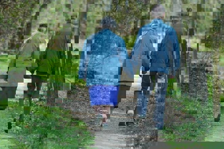 Two old people walking together while holding hands